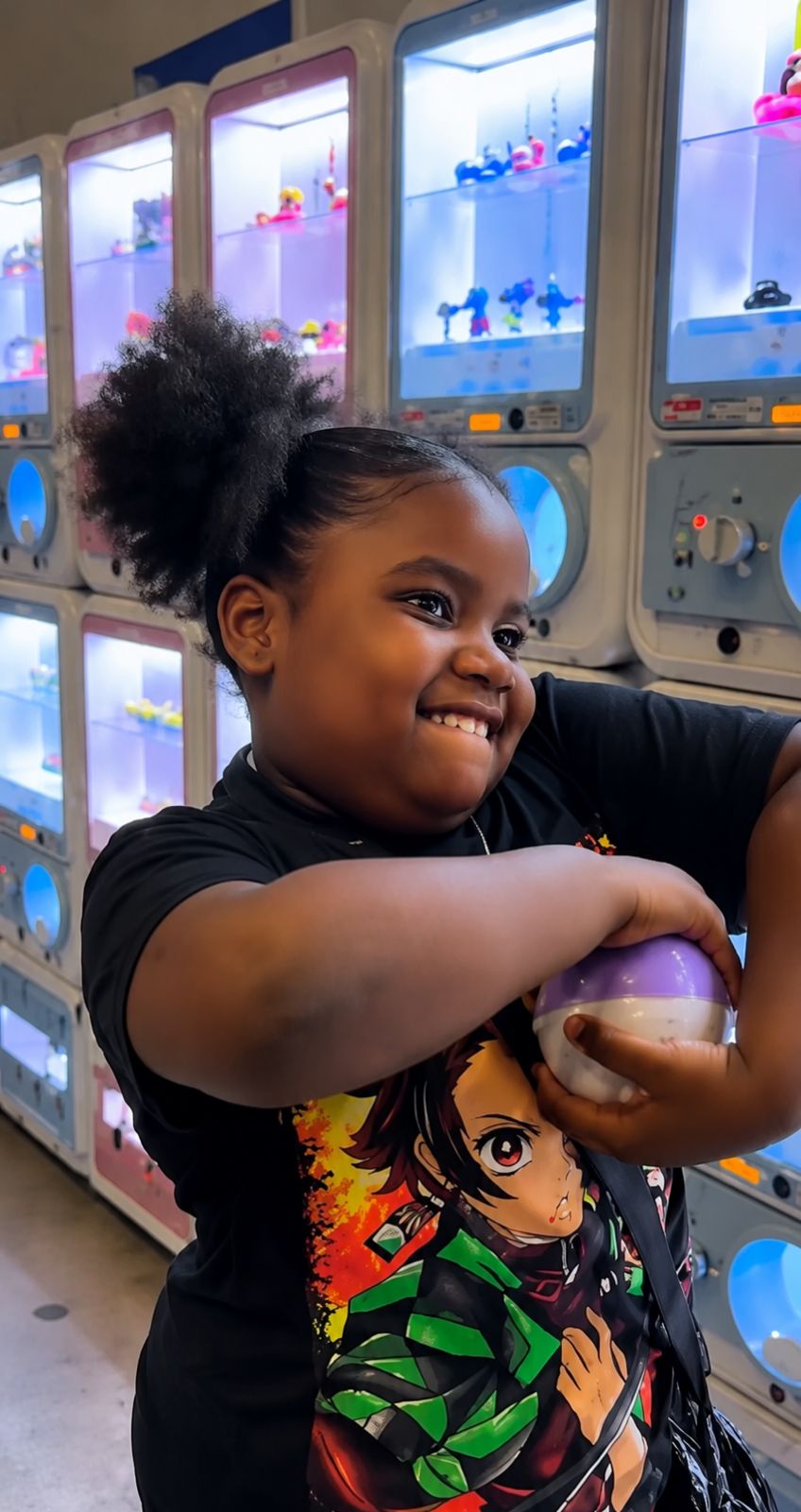 Niña feliz abrazando una cápsula GASHAFUNKO
